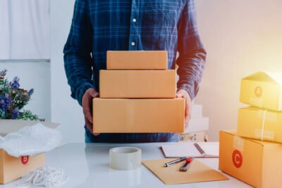 Closeup view of man online store small business owner seller entrepreneur packing package post shipping box preparing delivery parcel on table. entrepreneurial self employed business concept.